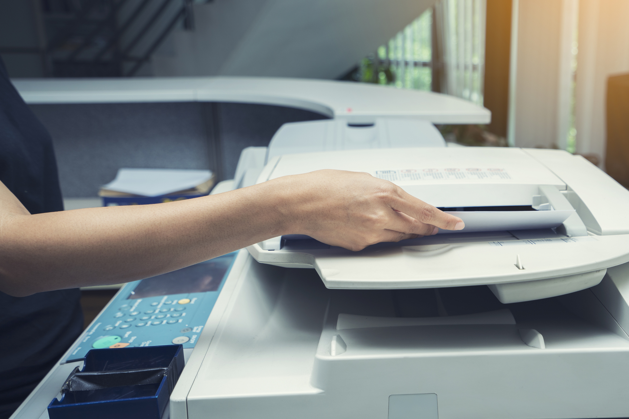 woman hands putting a sheet of paper into a copying device