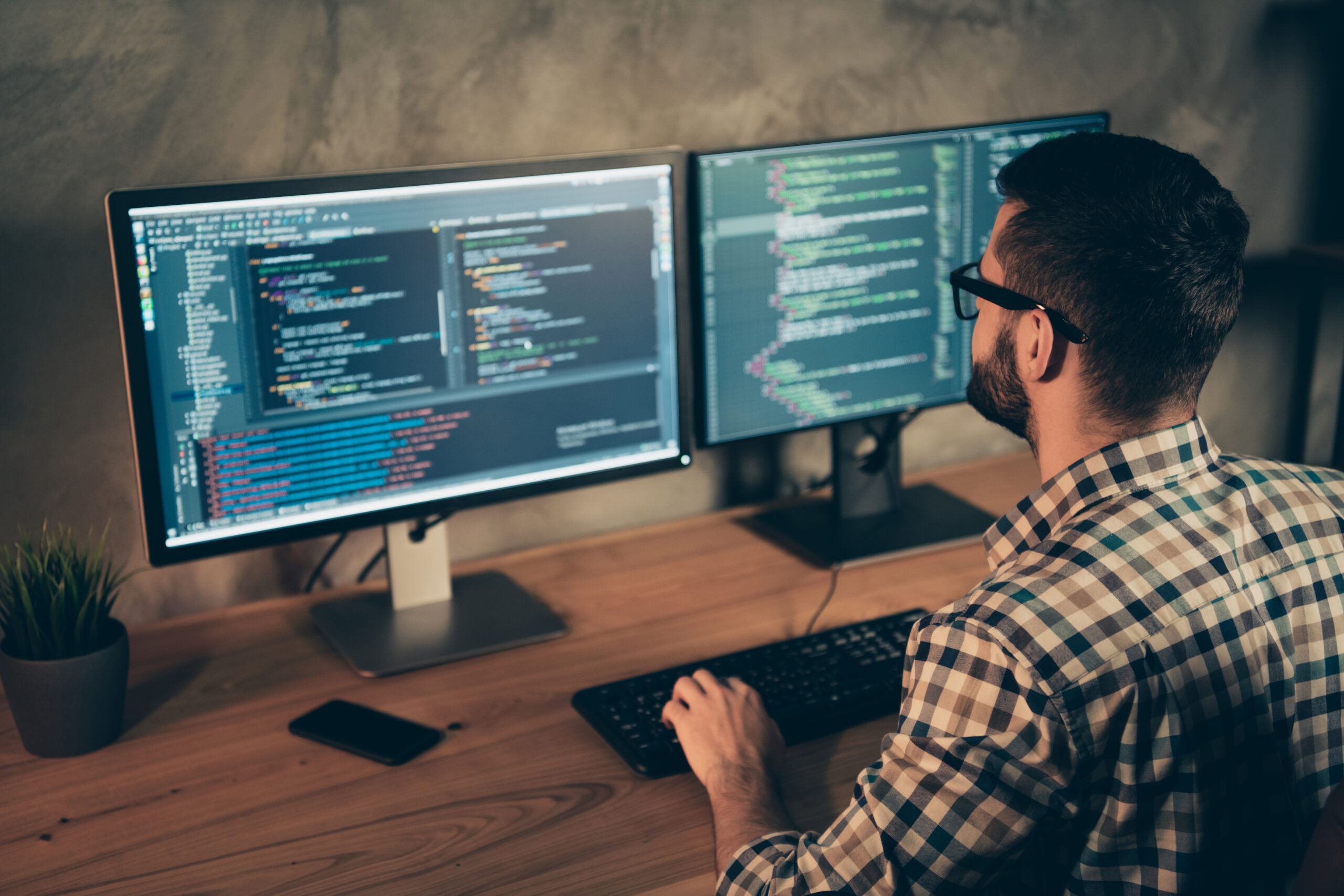 Profile side view of his he nice bearded guy wearing checked shirt professional, expert html data base structure screen at wooden industrial interior work place station signifying Managed IT services.