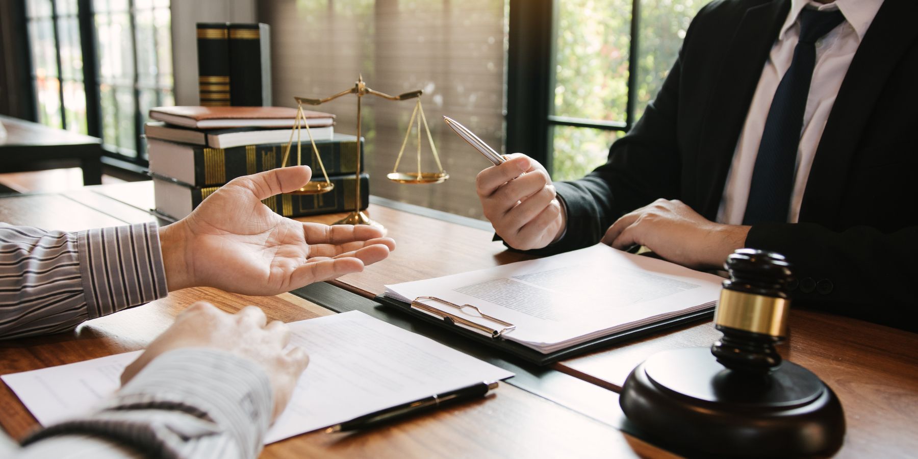 Close up of attorneys at a law office with the scales of justice, a gavel, and legal briefs on a desk