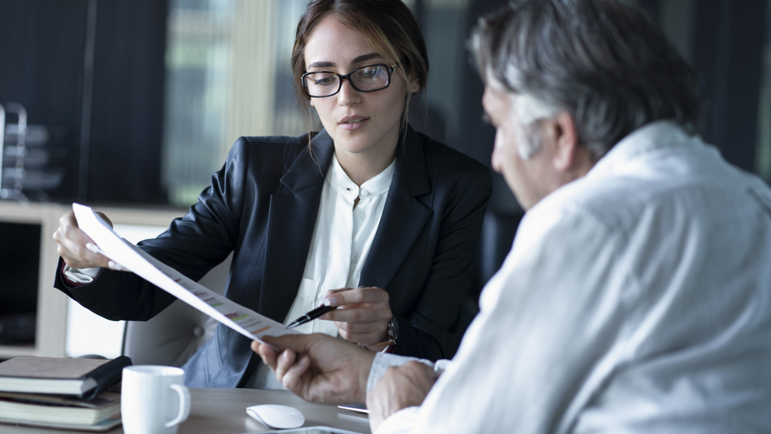 Two business professionals sit at a table reviewing a document conceptualizing a copier lease.