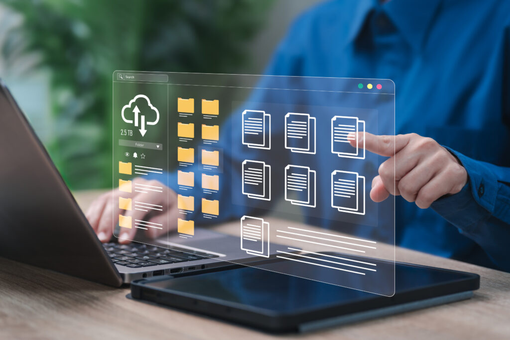 Close up of an office worker typing on a laptop with an overlay of a file manager with icons of documents, file folders, and a cloud download signifying digital records conversion services.