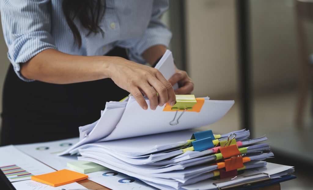 Close up of an office employee sifting through a stack of collated documents signifying how some businesses require high volume printing solutions.