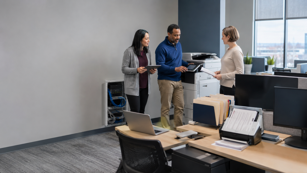 Business professionals conducting an office technology assessment of printing equipment, IT systems, and document workflows.