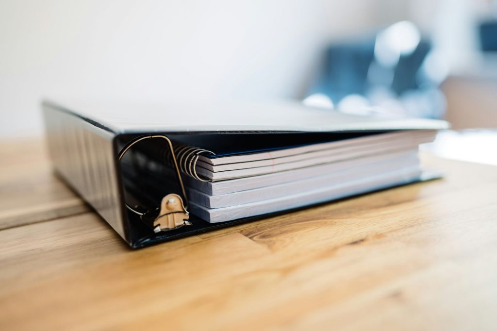 Thick ring binder of documents on a wooden table