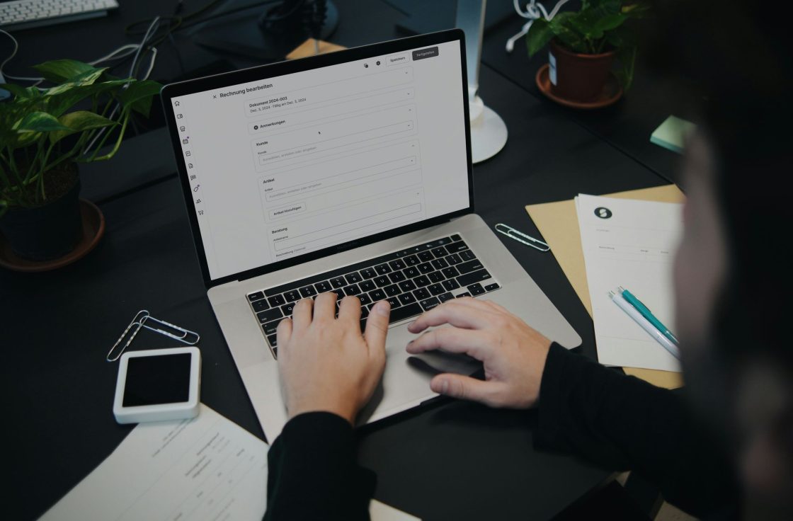 Person typing on a laptop at a desk with notes