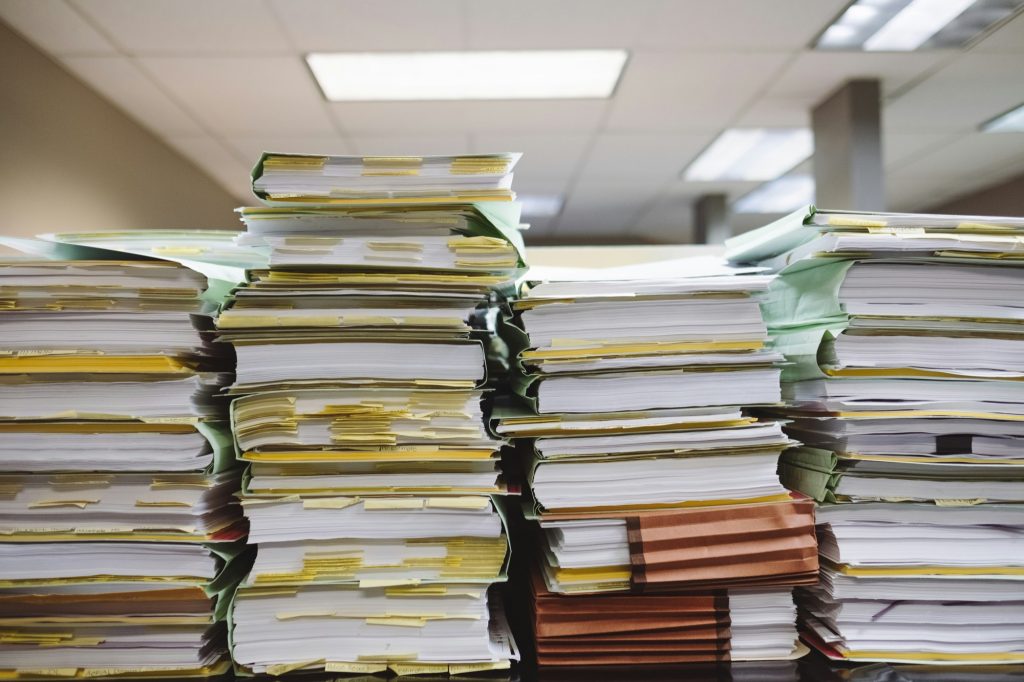 Tall stacks of tabbed case files and folders on an office desk
