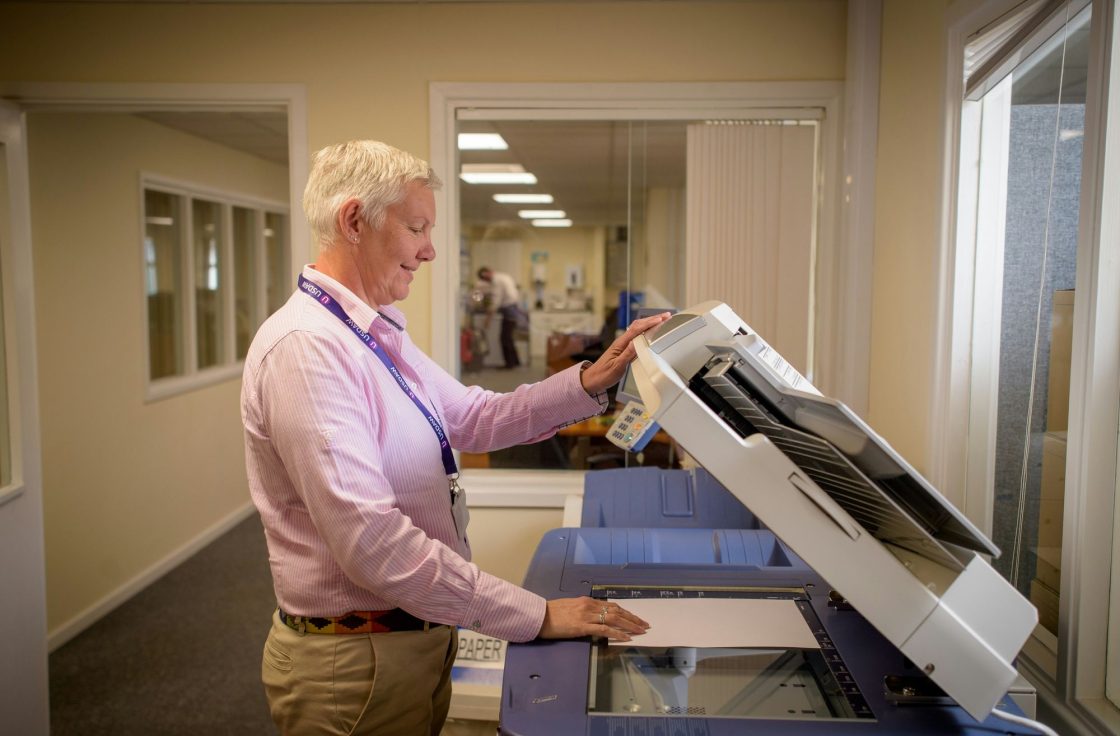 Technician servicing a copier in an office hallway