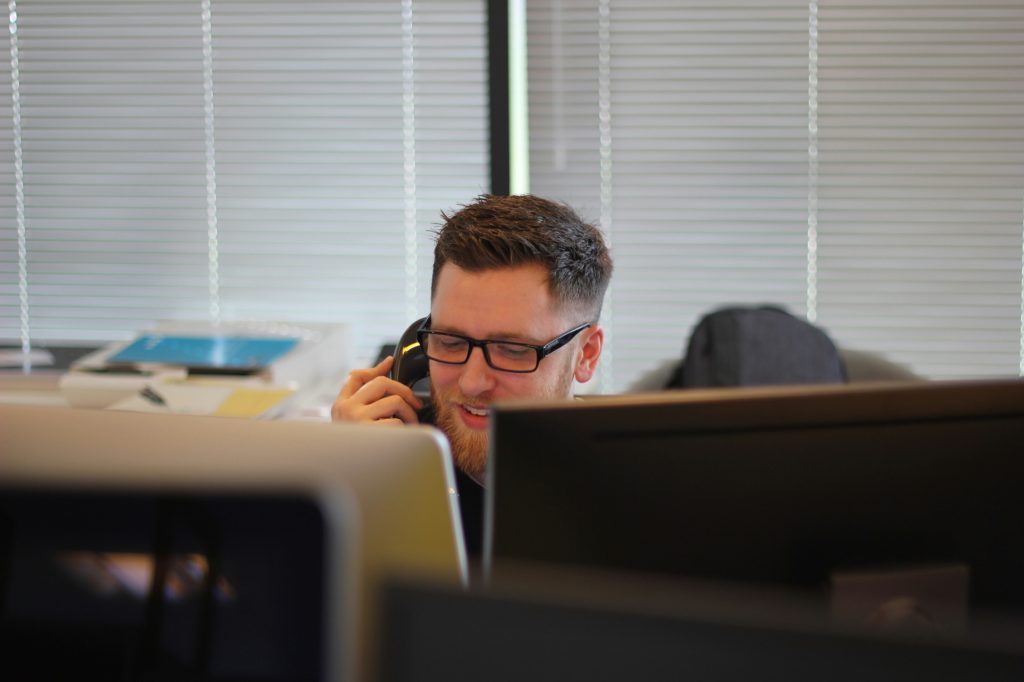 Help desk technician on the phone at his workstation