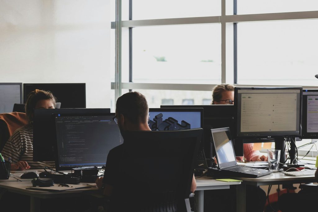 Staff working at multi-monitor workstations in a bright office