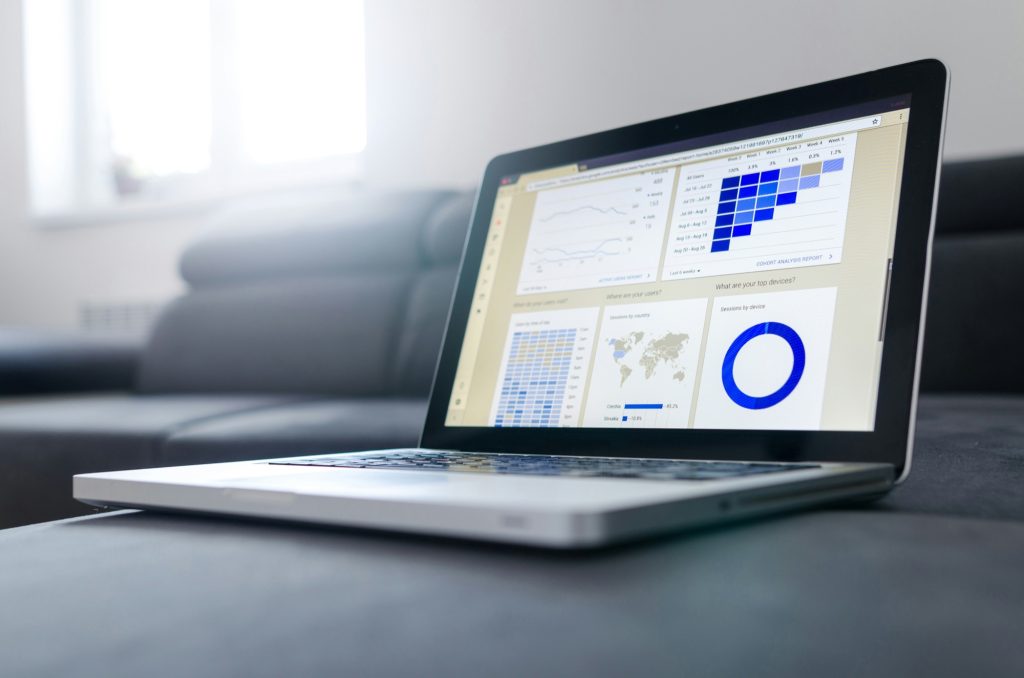 Laptop on a sofa showing a software dashboard with charts
