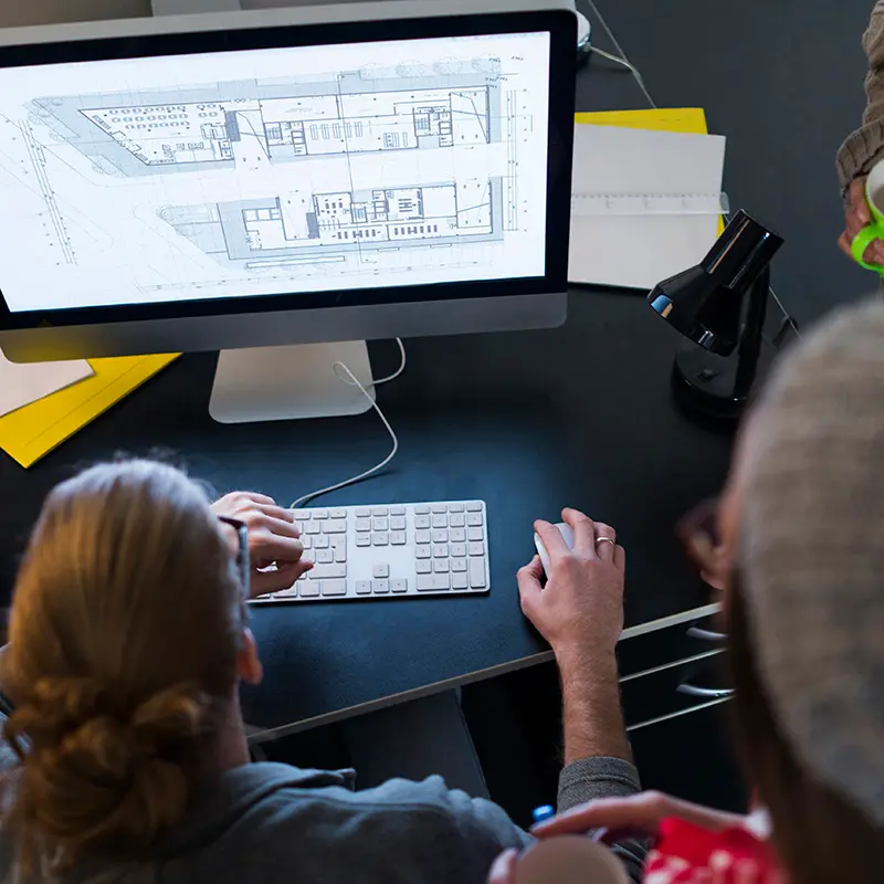 Designers reviewing large-format plans on a desktop monitor