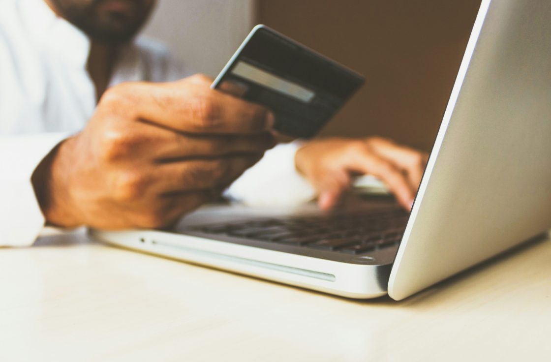Person holding a payment card while using a laptop