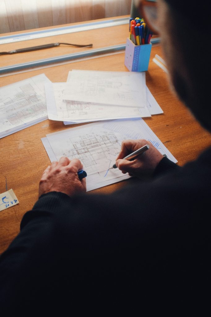Architect sketching plans by hand at a wooden drafting desk