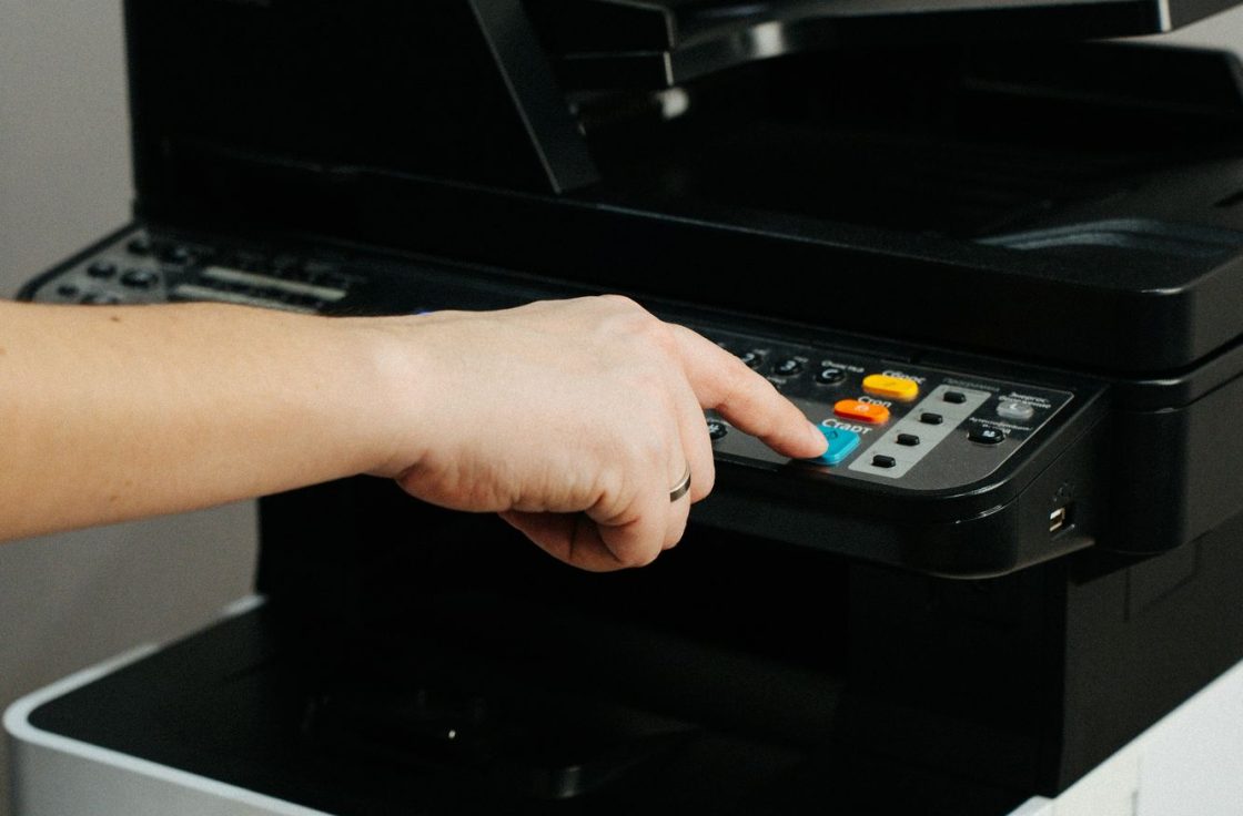 Hand pressing the control panel of an office multifunction printer