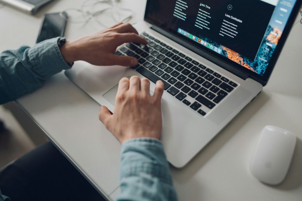 Person working on a laptop with a mouse beside it