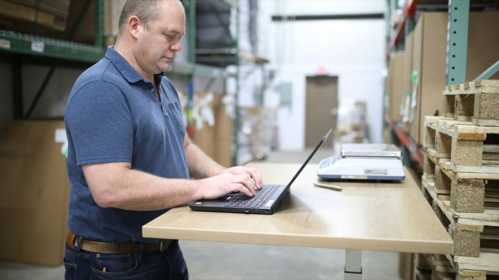 Warehouse manager working on a laptop at a standing desk