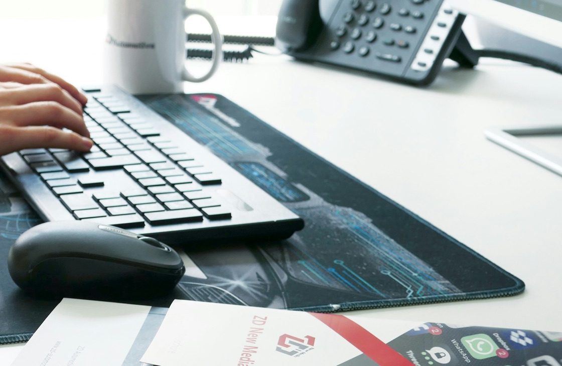 Hands typing on a keyboard at a desk beside a desk phone